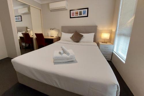 a bedroom with a white bed with a towel on it at Ellard Bed & Breakfast in Perth