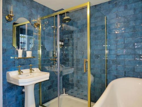 a blue tiled bathroom with a sink and a shower at The Hall - Historic Grade I-listed Jacobean Mansion in Bradford on Avon
