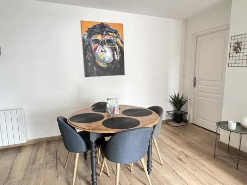 une table à manger avec des chaises et une peinture d'un chien dans l'établissement Appartement 2 chambres Le Descartes, à Calais