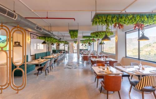 a restaurant with tables and chairs and plants at Velmore Kasauli Operated by Royal Orchid Hotel Ltd. in Kasauli