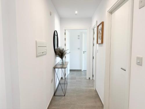 un couloir aux murs blancs et un miroir sur une table dans l'établissement E1 Suites & Spa aparthotel style - Gym & Spa, à Gibraltar