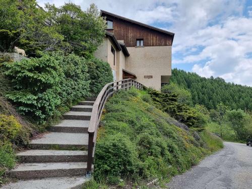 un escalier menant à un bâtiment sur une colline dans l'établissement Studio pour 2 avec balcon sud, proche station - FR-1-393-20, à Saint-Michel-de-Chaillol