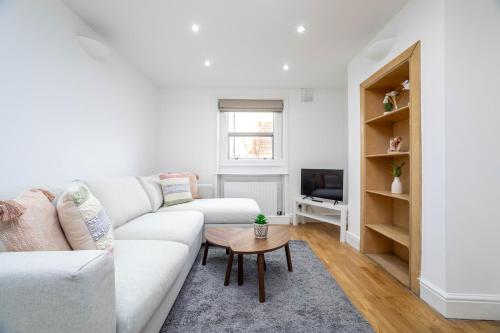 a white living room with a white couch and a table at 3 bedroom house in Notting Hill in London