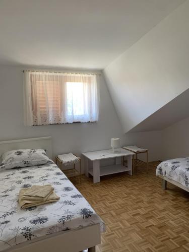 a bedroom with two beds and a table and a window at Apartments Milan in Peroj