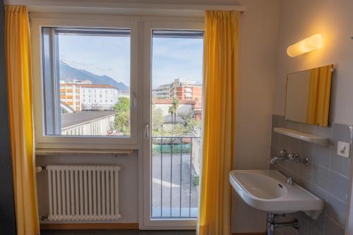 a bathroom with a sink and a window with a view at Locarno Youth Hostel in Locarno