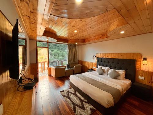 Himalayan Hill Queen Resort, Manali في مانالي: غرفة نوم بسرير كبير بسقف خشبي