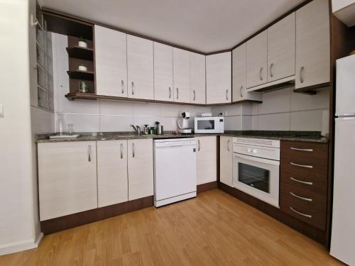 a kitchen with white cabinets and white appliances at Vista Corazón in Benidorm