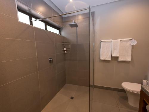 a bathroom with a glass shower with a toilet at ANEW Resort Hunters Rest Rustenburg in Rustenburg