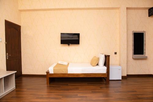 - une chambre avec un lit et une télévision murale dans l'établissement CROWN REGENCY- BADULLA, à Badulla