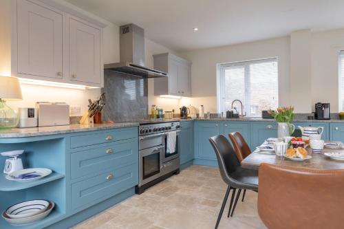 a kitchen with blue cabinets and a dining table at Buntings in Walberswick