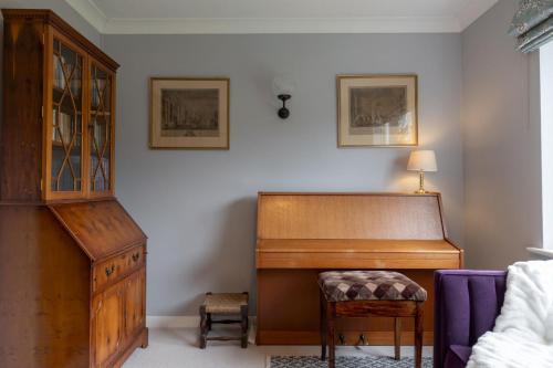 a room with a wooden piano and a cabinet at Buntings in Walberswick