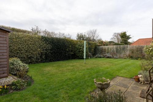 a garden with a fence and a grass yard at Buntings in Walberswick