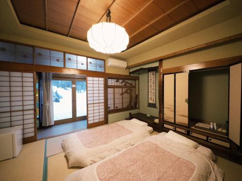 a bedroom with two beds and a tv and windows at Otarunishikien in Otaru