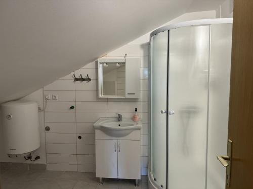 a white bathroom with a sink and a shower at Apartments Milan in Peroj