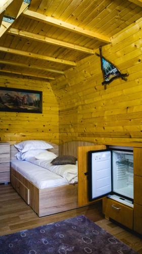 a bed in a wooden room with a television at Rosa&Vera in Ucea de Sus