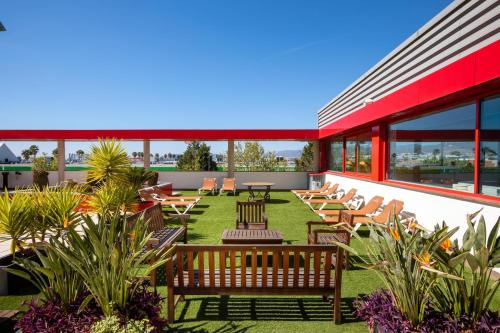 un patio al aire libre con sillas, mesas y ventanas en Alexandre Hotel Frontair Congress en Sant Boi de Llobregat