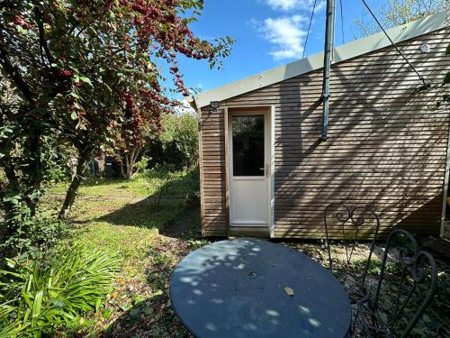 una pequeña casa con una puerta blanca y una mesa en Maisonnette studio avec jardin, en Angers