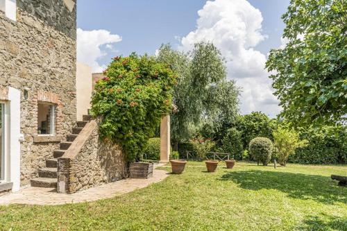 a garden with a stone wall with a tree and potted plants at Casale Le Pietre in Marta