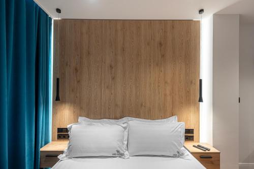 a bed with white pillows and a wooden headboard at A&N Athens Luxury Apartments - Acropolis in Athens
