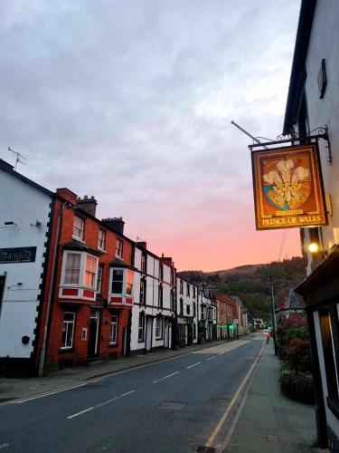 an empty street with a sign hanging from a building at Prince of wales accommodation in Llangollen