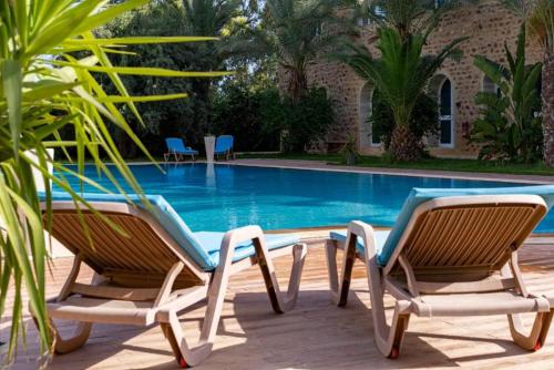 two chairs sitting next to a swimming pool at Hôtel Dar Mhana in Hammamet