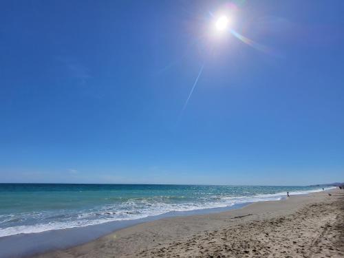 a beach with the sun shining over the ocean at Al Andalus Thalassa in Vera, Almeria in Vera