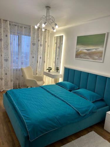 a bedroom with a blue bed and a chair at Apartment on Shevchenka in Cherkasy