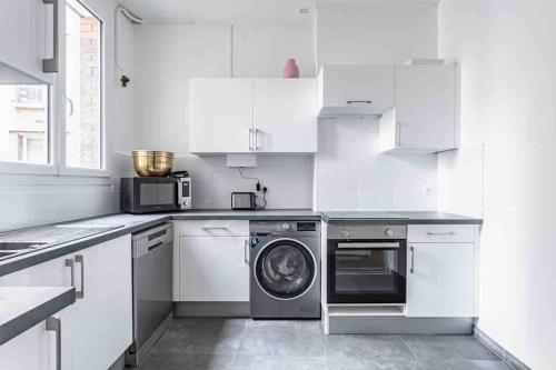 Il comprend une cuisine blanche équipée d'un lave-linge et d'un lave-vaisselle. dans l'établissement Grand appartement familial, à Paris