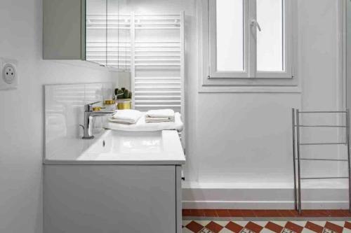 une salle de bain blanche avec un lavabo et une fenêtre dans l'établissement Grand appartement familial, à Paris