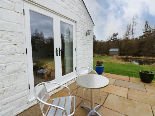 a patio with two chairs and a table and a window at Woodland View in Bishop Auckland