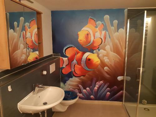uma casa de banho com uma pintura de peixe de palhaço na parede em Ferienhaus an der Höh' em Zellingen