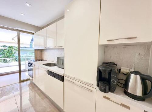 une cuisine blanche avec un évier et une cuisinière dans l'établissement Sweet home+terrasse de 60m2 ,2 mn from croisette beach, à Cannes
