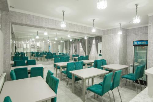 a dining room with white tables and green chairs at HOTEL MERCURI-MERIDIAN in Bukhara