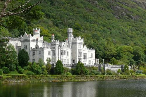 a castle on the shore of a body of water at Clifden Glen Cottage in Clifden