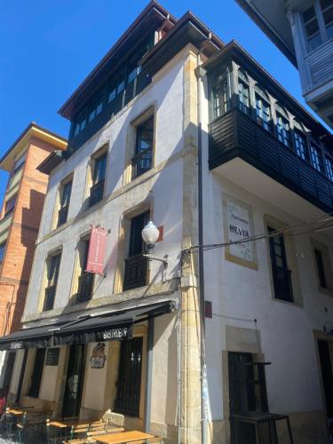 a white building with a balcony on the side of it at Apartamentos Hevia in Villaviciosa