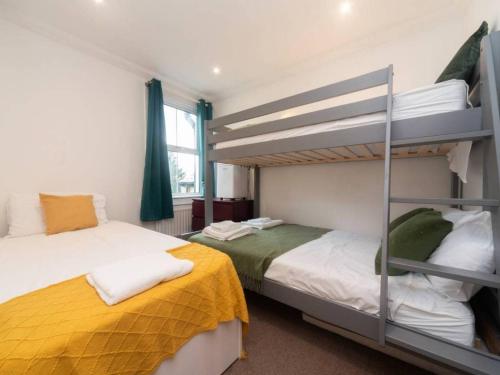 a bedroom with two bunk beds and a window at Charming Period Home near Surbiton with Garden in London