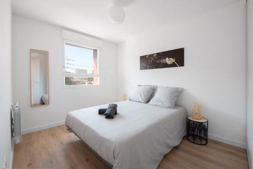 a white bedroom with a large white bed and two windows at T2 avec parking gratuit - proximité gare in Toulouse