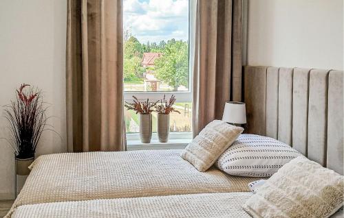 a bed with two pillows and a window with plants at 2 Bedroom Beautiful Apartment In Biskupiec in Biskupiec