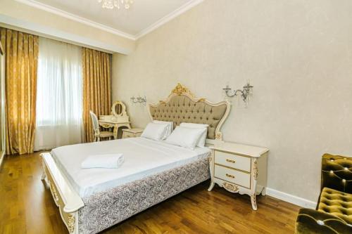 um quarto com uma grande cama branca e uma cadeira em VIP Apartment MANDARIN em Baku