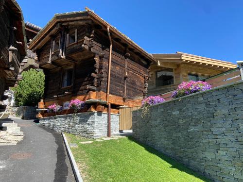 a large wooden house with a stone wall at Chalet Coral und Zermatter Stadel in Zermatt