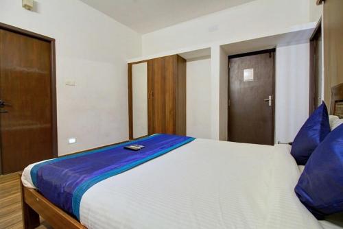 ein Schlafzimmer mit einem großen weißen Bett mit blauen Kissen in der Unterkunft Dakshin Stays in Chennai