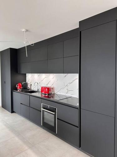 une cuisine avec armoires noires et appareils rouges dans l'établissement t4 avec terrasse face mer, à Ajaccio