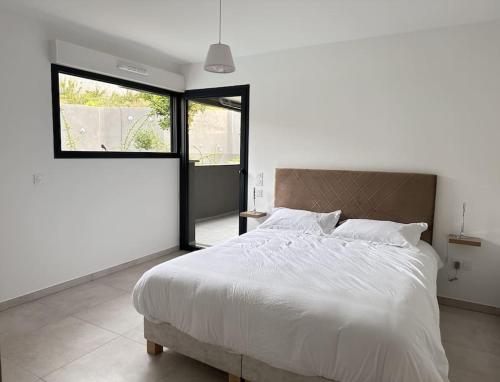 une chambre avec un grand lit blanc et une fenêtre dans l'établissement t4 avec terrasse face mer, à Ajaccio