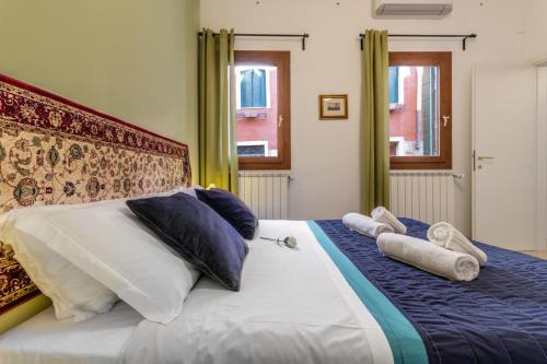 uma cama grande com almofadas e toalhas em Veneziacentopercento Zoto Apartment em Veneza