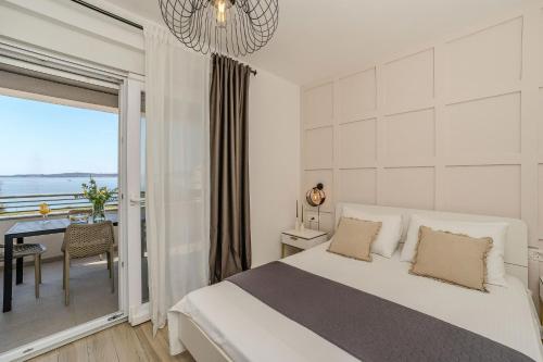 a white bedroom with a bed and a balcony at Luxury Home Polo in Bibinje