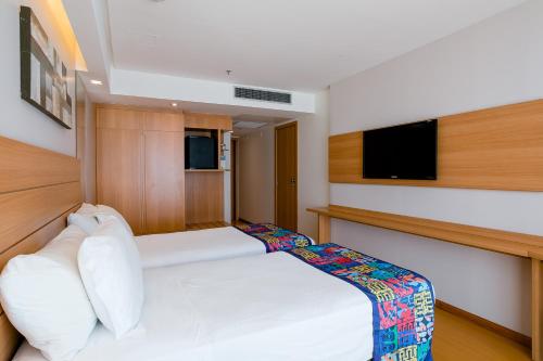 a small bedroom with a bed and a tv at Arena Copacabana Hotel in Rio de Janeiro