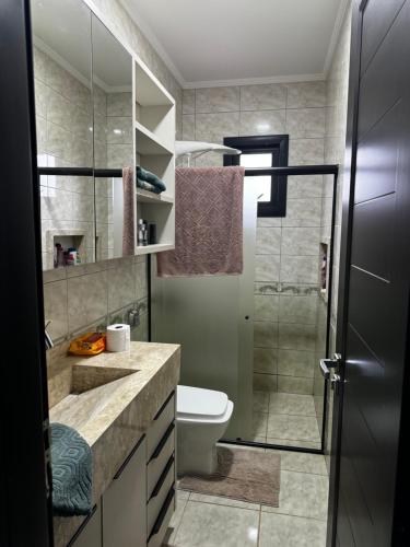 a bathroom with a toilet and a glass shower at Casa confortável in Foz do Iguaçu