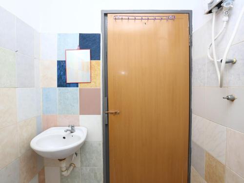 een badkamer met een wastafel en een houten deur bij KB Rest Inn-Twin Single in Kota Bharu