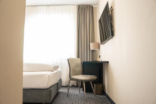 a hotel room with a bed and a chair and a window at Remstal Hotel in Weinstadt