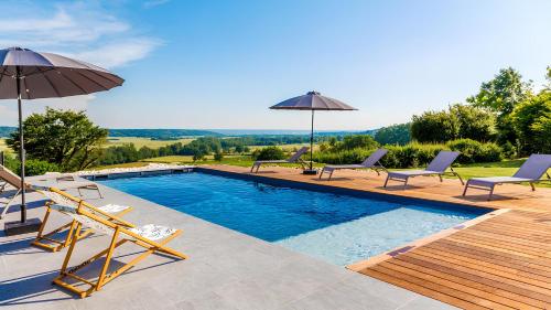 a swimming pool with chairs and umbrellas on a house at Gîte et chambres d'hôtes - La Maison du Grand Bossieu in Bossieu
